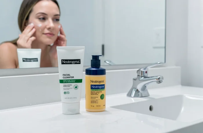 Produits de soin dermatologique Neutrogena disposés sur un lavabo de salle de bain avec reflet miroir
